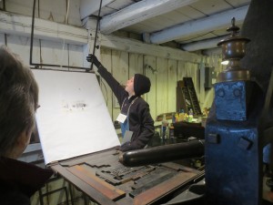 "Printer's Devil" Isaac prints bookmarks for the visitors.